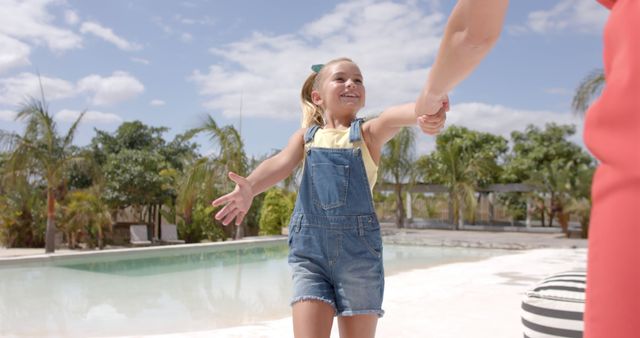 Happy caucasian mother with daughter holding hands at swimming pool at beach house. Vacation, free time, summer and family.
