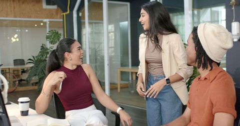 Multiracial Team Collaborating and Laughing in Modern Open Office with Casual Workspace