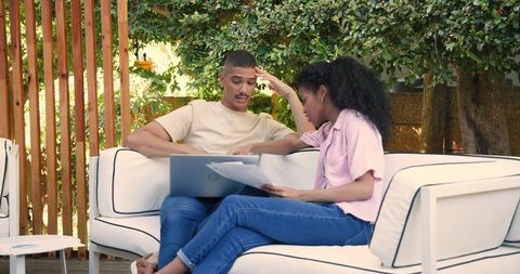 Couple discussing finances with laptop on outdoor patio