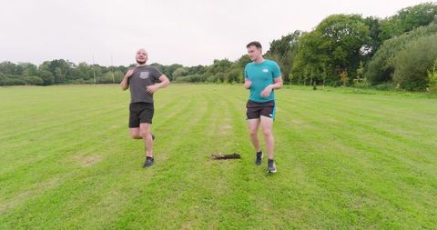 Two men jogging on green field, promoting outdoor fitness