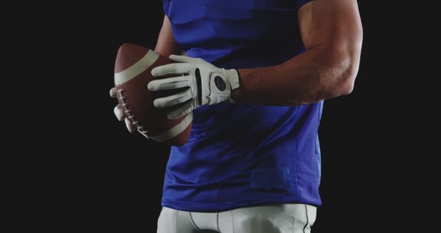 Athlete Holding Football Wearing Blue Jersey on Black Background - Download Free Stock Images Pikwizard.com