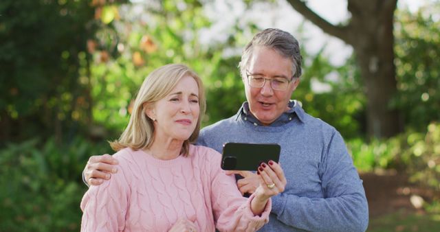 Image of happy caucasian senior husband and wife making image call on smartphone in garden. Family, domestic life and togetherness concept digitally generated image.
