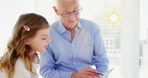 Grandfather Teaching Young Girl Tablet Use by Sunny Window