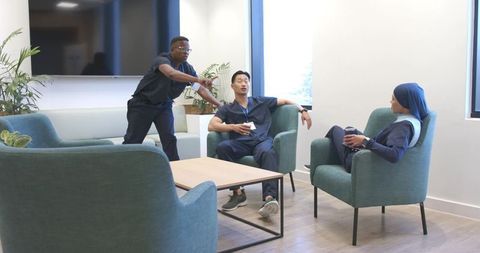 Multicultural healthcare team taking coffee break in modern staff lounge with plants