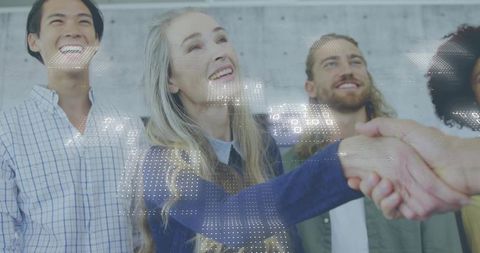 Mature woman shaking hands amid team embracing digital collaboration and networking