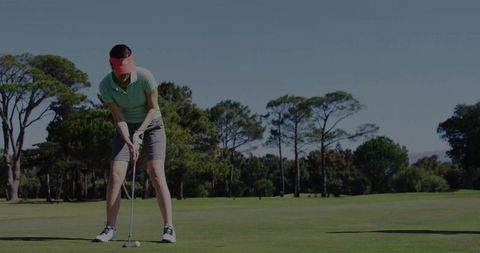Woman aligning putt in bright golf outfit on lush green course