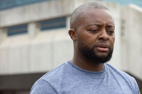 Pensive african american man standing by urban concrete facade closeup with overcast mood