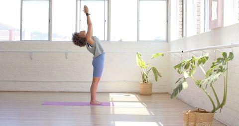 Woman Practicing Stretching Exercise in Sunlit Yoga Studio