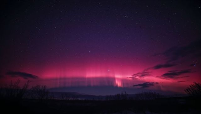 Dancing magenta aurora curtains over tundra nightscape illuminating star field