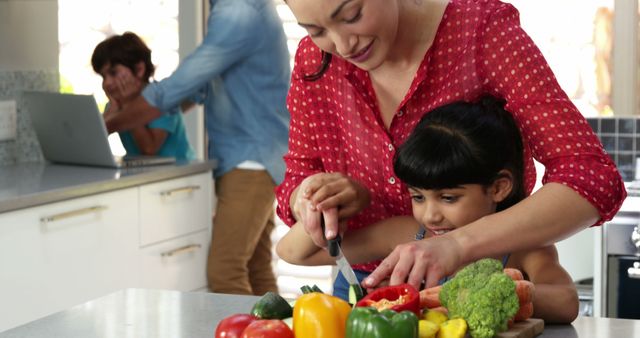Mother chopping vegetables with daughter, teaching healthy eating habits. Perfect for promoting family activities, healthy eating, cooking classes, parenting tips, and domestic life.