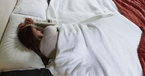 Peaceful Woman Relaxing in Cozy White Bedding in Minimalist Bedroom