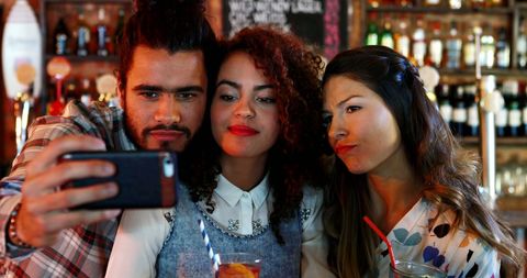Friends Capturing Memories with Selfies at Lively Pub