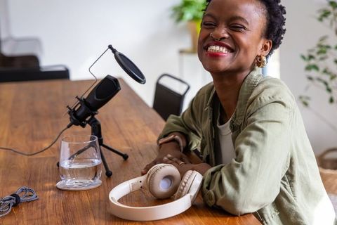 African american woman smiling while recording podcast in modern minimalist home studio