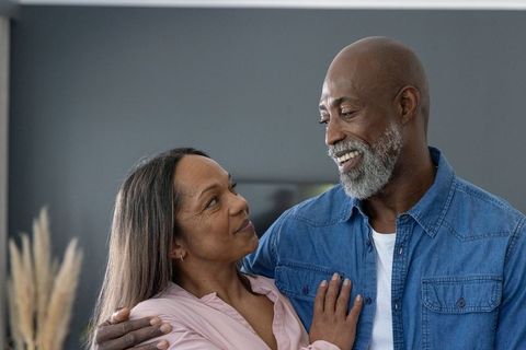 Affectionate mature couple sharing romantic smile at home embracing in warm modern living room