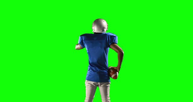An athlete wearing a blue jersey and helmet runs with an American football. Green screen background allows for easy editing and insertion into different scenes. Suitable for sports montages, advertisements, educational videos, and other media projects specializing in American football.