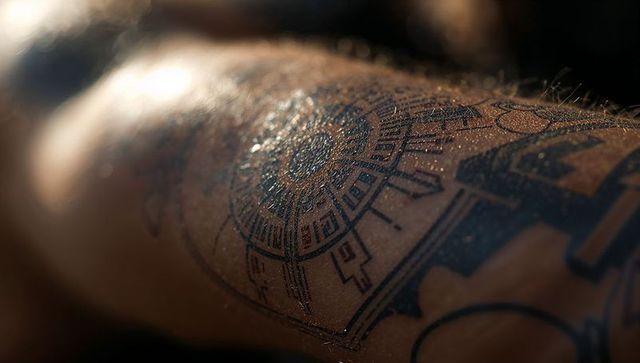 Close-up of geometric circular tattoo with shimmering water droplets