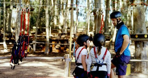 Family Prepares for Adventure Ropes Course in Forest