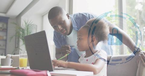 Black father guiding daughter on laptop at home, teaching online with security overlay
