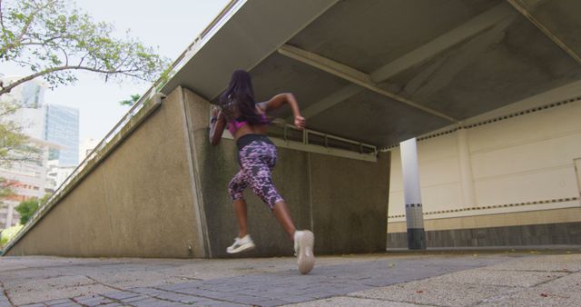 African american woman exercising outdoors running under bridge in the city. healthy outdoor lifestyle fitness training.