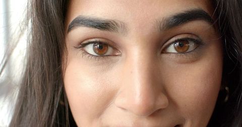 Closeup Indian woman making direct eye contact with warm brown eyes and natural makeup
