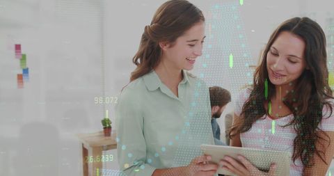 Businesswomen discussing data on digital tablet in modern workspace