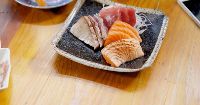 Sashimi platter on rustic wooden table featuring various types of sliced raw fish, ideal for promoting Japanese cuisine, seafood festivals, restaurants, or culinary blogs focusing on gourmet dining.