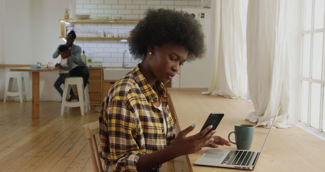 Woman Working at Laptop Using Smartphone in Bright Kitchen - Download Free Stock Images Pikwizard.com