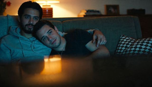 Male couple cuddling on sofa, sharing cozy night in, intimate lgbtq+ home moment