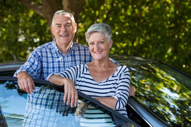 Portrait of smiling senior couple leaning on car door