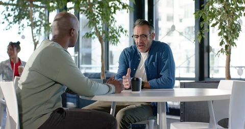 Multiracial colleagues discussing ideas over coffee in modern coworking lounge