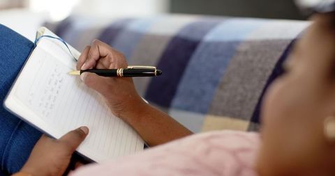 Woman Reflectively Journaling at Home on Cozy Couch