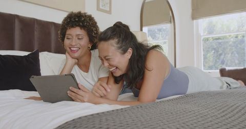 Friends Relaxing with Tablet in Cozy Bedroom Setting