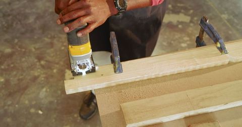 Craftsman Skillfully Using Handheld Router on Wooden Plank