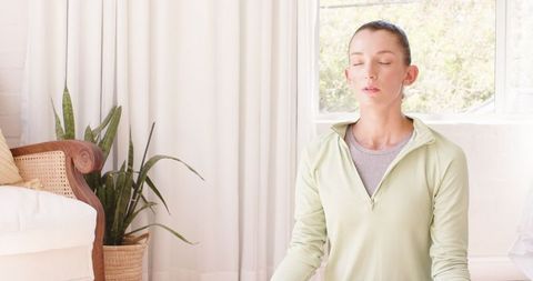Woman Practicing Mindfulness Meditation at Home Near Window