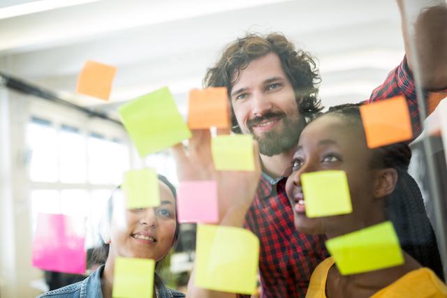 Creative professionals brainstorm using colorful sticky notes in an office environment. Ideal for illustrating teamwork, collaboration, and creative planning in business or design contexts.
