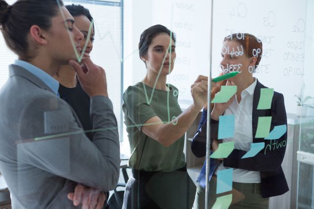 Group of executives collaborating on a project using sticky notes in an office. Ideal for depicting teamwork, brainstorming sessions, business planning, and corporate strategy meetings.