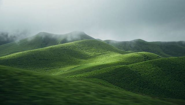 Sunlit rolling green hills with low mist over undulating moorland panorama wide view