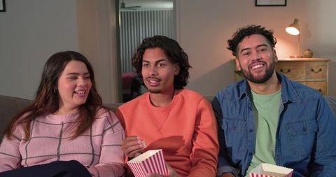 Friends enjoying movie night on couch with popcorn and cozy living room atmosphere