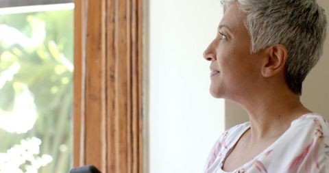 Contemplative Senior Woman Looking Out Window During Daytime