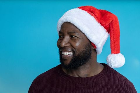African american man wearing santa hat smiling turquoise backdrop festive holiday headshot