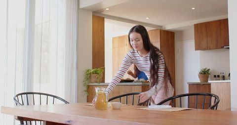 Asian Mother and Daughter Setting Dining Table in Cozy Kitchen