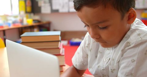 Focused young boy using laptop in classroom learning environment