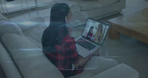 Woman engaging in virtual meeting on sofa at home