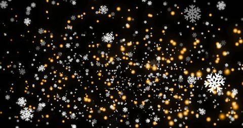 Glittering snowflakes floating against dark backdrop with warm golden bokeh lights