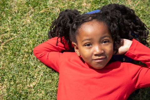 Smiling Girl in Red Shirt Relaxing on Grass