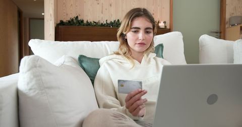Woman using laptop for online shopping in cozy living room