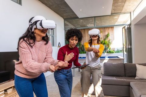 Diverse women experiencing virtual reality game in modern living room with vr headsets