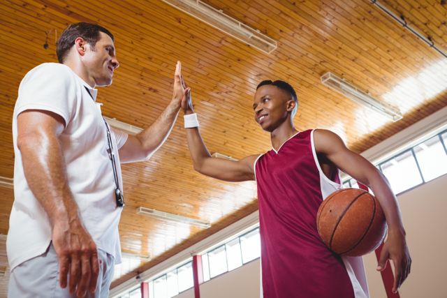 Low angle view of basketball player high fiving with coach - Download Free Stock Photos Pikwizard.com