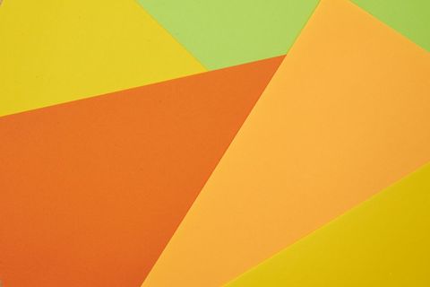 Layered orange yellow green paper creating bold geometric abstract background for design