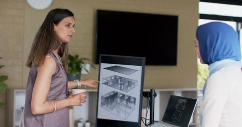 Indian women architects collaborating over 3d floor plans on monitor in modern office